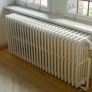 Beeco's Plumbing heating technician bleeding air from a residential cast iron radiator in Bucks County