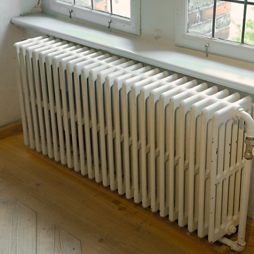 Beeco's Plumbing heating technician bleeding air from a residential cast iron radiator in Bucks County